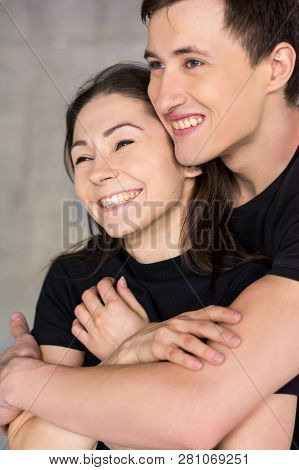Affectionate Couple Hugging Close Up. Young Handsome Man Hugging His Girlfried, They Are Laughing An
