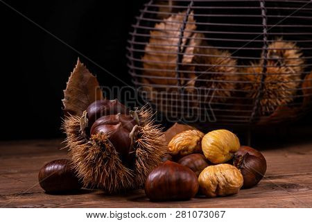 On The Rustic Wooden Table A Pile Of Fresh And Roasted Chestnuts