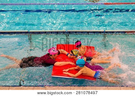 Poznan, Poland - January 26, 2019: Woman Holding A Mat With 4 Children During Swimming Lesson In A P