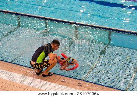Poznan, Poland - January 26, 2019: Instruction Helping Boy On A Swim Stick During Swimming Lesson In