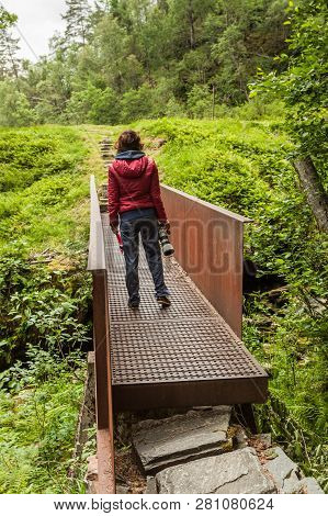 Tourist Woman With Camera On Staircase To Walk Up To Svandalsfossen In Norway, Waterfall In Norwegia