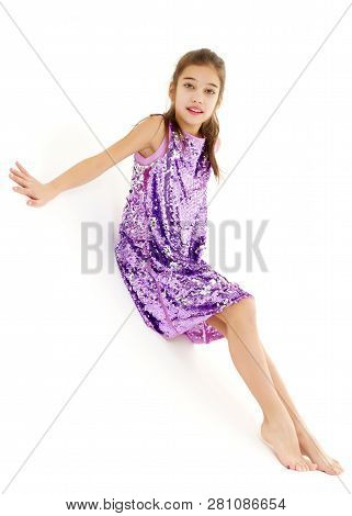 A Cute Little Girl Leaned Against A White Wall. Cyclorama In Studio. Isolated On A White Background.