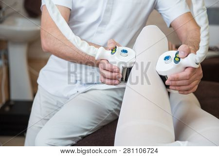 Procedure laser lipolysis of the woman hips in a beauty center.