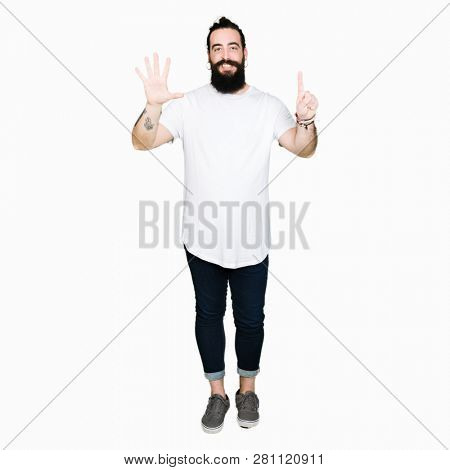 Young hipster man with long hair and beard wearing casual white t-shirt showing and pointing up with fingers number six while smiling confident and happy.
