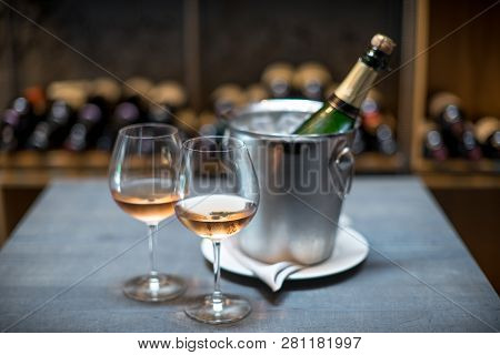 Two Cold Glasses Of Sparkling Wine. The Wall Ow Wine Bottels On Background.