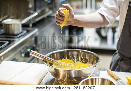 Kitchen In The Restaurant. Chef Is Preparing A Yellow Sauce. Squeezes Juice From A Lemon.