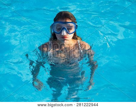 Cute Happy Young Girl In Goggles Swimming And Snorking In The Swimming Pool