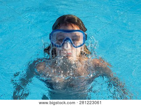 Cute Happy Young Girl In Goggles Swimming And Snorking In The Swimming Pool
