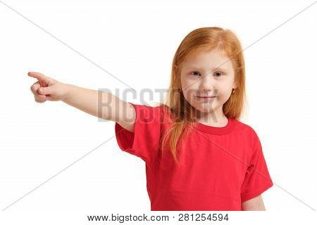 Education, School And Imaginary Screen Concept - Cute Little Girl Pointing In The Air Or Imaginary S
