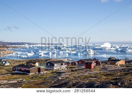 Rodebay, Greenland - July 09, 2018: Colorful Wooden Houses With Icebergs In The Background. Rodebay,