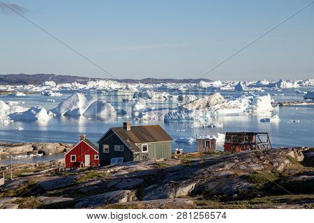 Rodebay, Greenland - July 09, 2018: Colorful Wooden Houses With Icebergs In The Background. Rodebay,