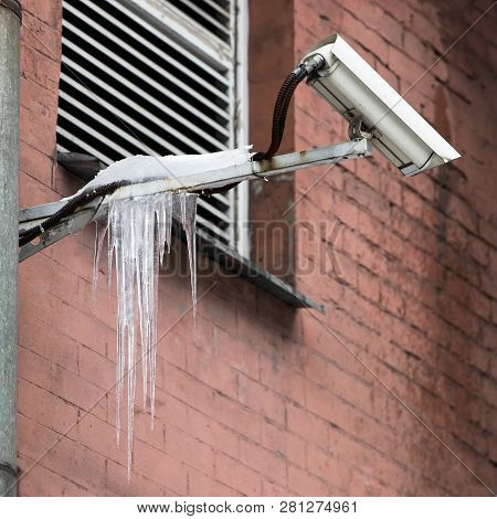 Video Surveillance Camera Covered With Sharp Icicles. Icing Of Constructions With Icicles. Thaw, Win