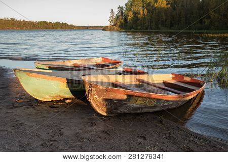 Old Shabby Wooden Fishing Colorful Boats On The Lake Shore During Sunset, Autumn Forest On Backgroun