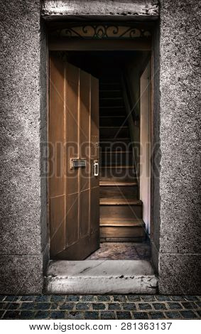 Half opened door showing a wooden stairway inside an old house, blur