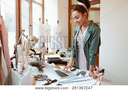 Checking Online Sales. Young Woman Tailor With Laptop Is Answering Emails