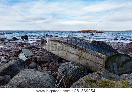Rowing Boat Upsidedown On A Rocky Beach