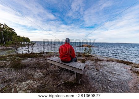 Man In Red Jacket Sitting On A Bench