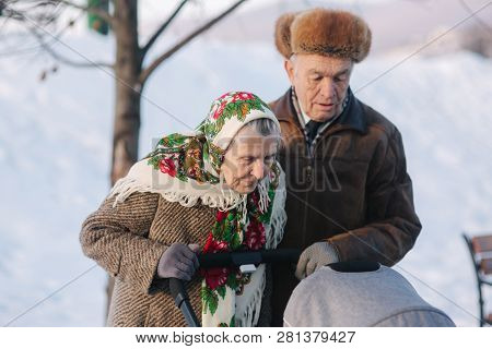 Grand Grandparents Walking With A Baby In Beautiful Pram. Winter Time