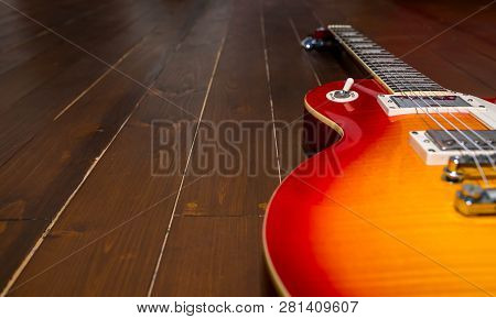 Sunburst Electric Guitar On Wood Floor Close Up, Space For Text.