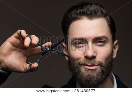 Portrait Of Stylish Hipster Man With Beard Holding Scissors Near Face. Barber Scissors And Straight