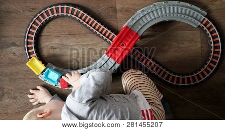 A Little Boy Plays A Children's Railway. Mom Is Watching Her Son From Above. The Child Is Fascinated