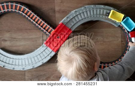 A Little Boy Plays A Children's Railway. Mom Is Watching Her Son From Above. The Child Is Fascinated