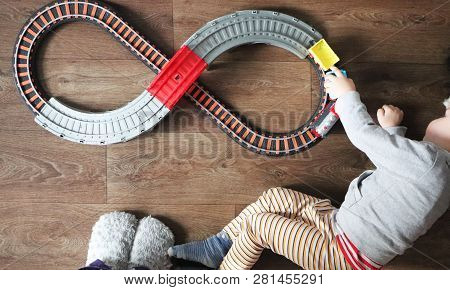 A Little Boy Plays A Children's Railway. Mom Is Watching Her Son From Above. The Child Is Fascinated