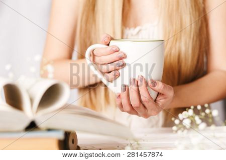 A Cup Of Tea In Womens Hands. Cozy Concept For Spring Morning. Spring Flower Tea In A White Cup On T