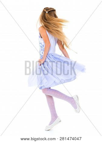 Happy Little Girl In A Lush Flowing Dress, Spinning. Her Hair Is Flying In The Wind. The Concept Of 