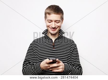 Happy young man in glasses typing sms on white background