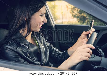 Happy Smiling Woman Holding Her Smart Phone Sitting Inside A Car. Female Driver Laughing Reading Mes