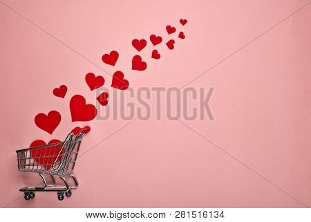Shopping trolley and decorative red hearts on pink background with copy space. Valentine's day, Mother's day,  wedding