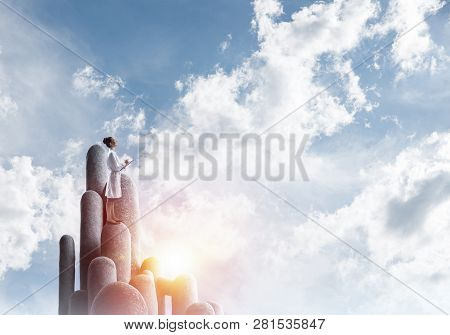 Young Female Doctor With Folder In Hands Satnding On Stone Column