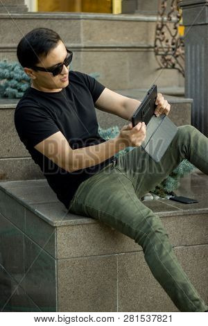 Gaming Asian Young Man With Tablet On Street