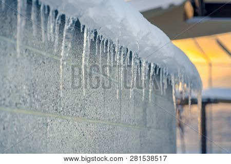 Sharp Transluscent Icicles Against Wall At Sunset