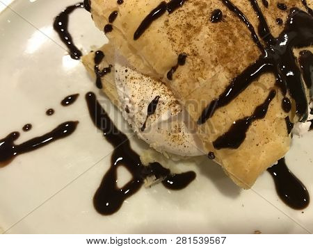 Close-up Of Delicious Pastry Stuffed With Meringue, Chocolate Sirup And Sprinkled Cinnamon.