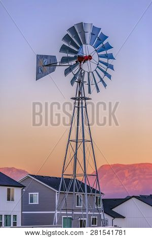 Windpump Against Homes Mountain And Sky In Utah