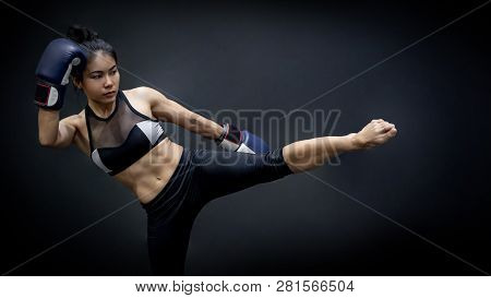 Young Asian Woman Boxer With Blue Boxing Gloves Kicking In The Exercise Gym, Martial Arts On Black B