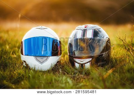 Two Motorcycle Helmets Lie On The Grass In The Sun