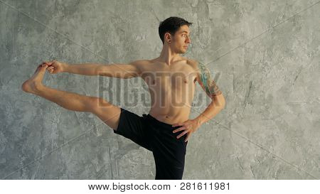 Male Yoga Master Stretching Leg In The Studio. Standing, Holding