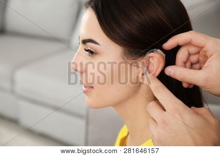 Man Putting Hearing Aid In Woman's Ear Indoors, Closeup