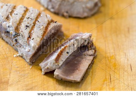 Chargrilled, Seasoned Tuna Steaks Cooked And Sliced On A Wooden Chopping Board