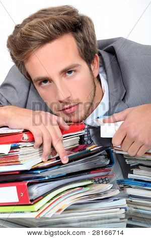 młody człowiek leżącej na biurku pełnym segregatorów i notebooki