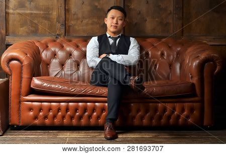 Successful Man Sitting On A Leather Couch, Putting His Foot On The Leg
