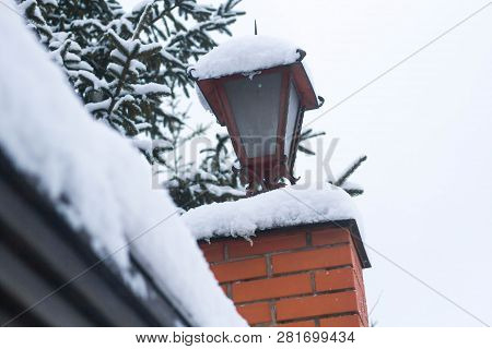 View Of The Street With Lamps. Fanar Over The Fence Of A Private House In The Snow