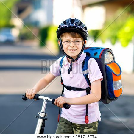 Active School Kid Boy In Safety Helmet Riding With His Scooter In The City With Backpack On Sunny Da
