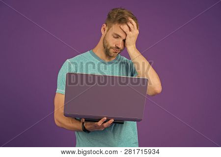 Tired Guy With Computer On Violet Background. Man In Blue Tshirt Work On Laptop On Purple Background