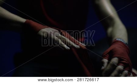 Close-up Of Boxer's Hand. Close-up Boxer Ties Injured Hands With Red Ribbon In Dark Locker Room, Pre