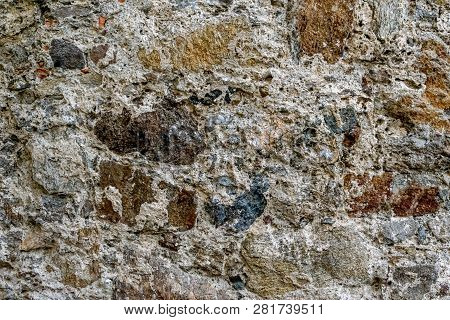 Closeup Of An Old Weathered Stone Wall, Partially Covered In Mortar. The Stone Wall Is And Vintage S