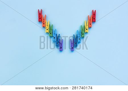 Many Colored Clothespins On A Blue Background. Multi-colored Clothespins Are Laid Out In The Shape O